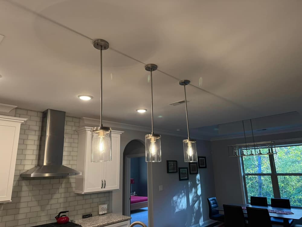 Modern kitchen featuring three hanging pendant lights above an island with stainless steel appliances.
